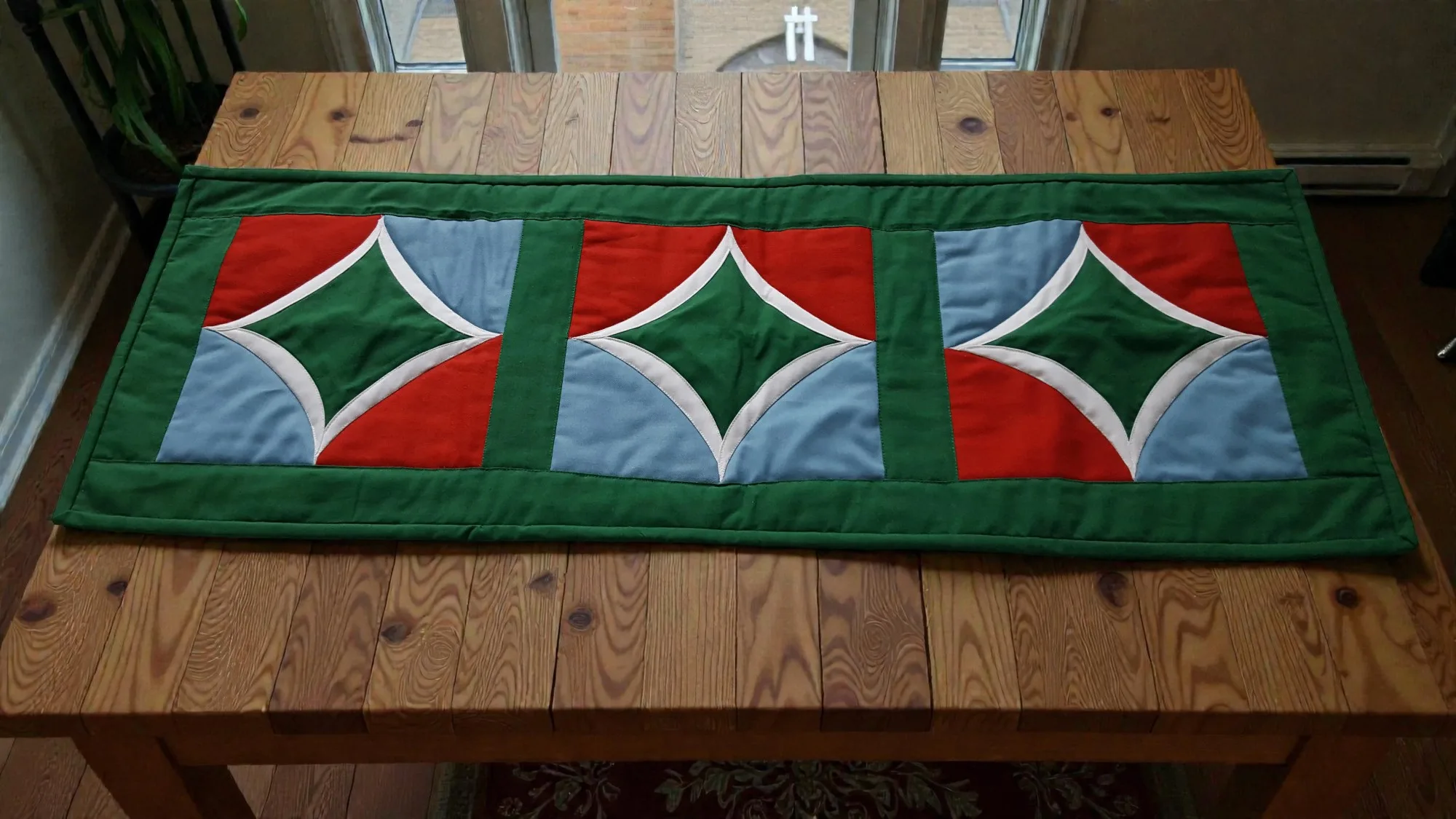 Table runner with geometric pattern in green, red, and blue on cotton